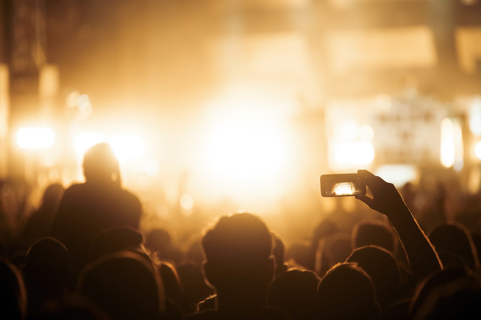 A crowd with phones raised at an evening concert